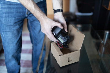 Adult man small business owner packing order box package shipping to customer. Entrepreneur packaging camera in box for delivery at home.