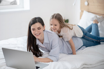 Kid and her mom watching a video on the laptop