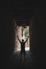 Vertical view of man outline with arms up in the air. Front view of person silhouette standing on a dark alley. Shapes and mockup concept of people doing poses.