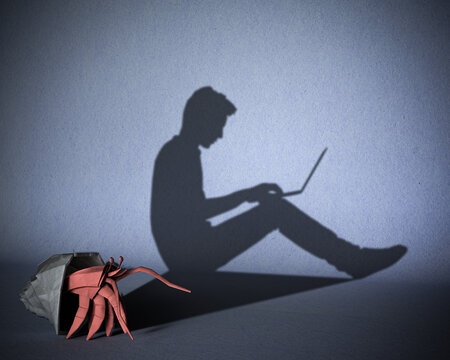 The concept of dependence of people on gadgets, the Internet. A paper figure of a hermit crab that casts a shadow on a guy sitting behind a laptop. 3d illustration.