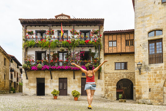 Horizontal view of unrecognizable woman with arm up in the air looking at the ancient spanish city of Santillana del Mar. Travel and holidays concept in european cities.
