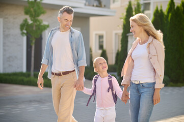 Parents and their daughter walking and holding hands