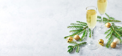 Glasses with sparkling wine type champagne with fir branches and golden Christmas tree decorations...