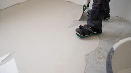 Spreading self leveling compound with trowel. Self-leveling epoxy. Leveling with a mixture of...