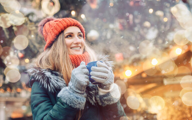 Beautiful woman drinking mulled wine on Christmas market in front of decorated three - obrazy, fototapety, plakaty
