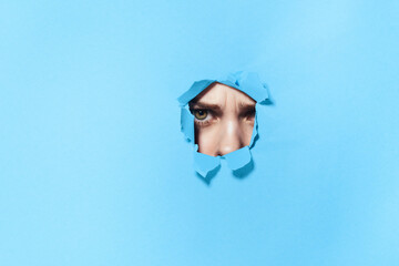 woman peeping through the holes in the poster blue studio background