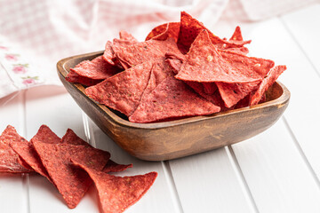 Salted tortilla chips triangle with red beet flavor in bowl.