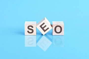 SEO - acronym from wooden blocks with letters, front view on blue background