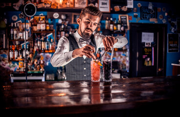 Young bartending mixes a cocktail at bar