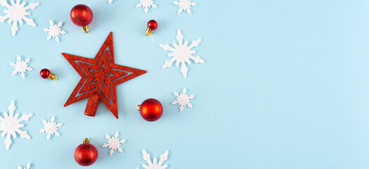 Christmas composition. Banner made of snowflakes, red decorations on blue background. Christmas, winter, new year concept. Minimal style. Flat lay, top view, copy space.