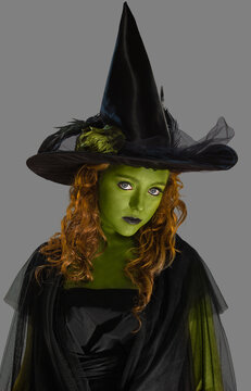 Portrait of a woman dressed as a witch with green body paint, looking into camera with attitude