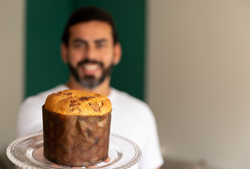 delicious Christmas panettone served by man holding, smiling in the background.