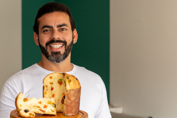 man smiling, looking at photo, showing delicious panettone on christmas day.