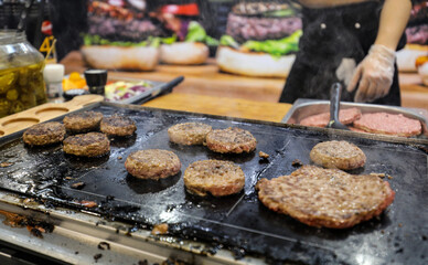 Beefburgers frying on a griddle.