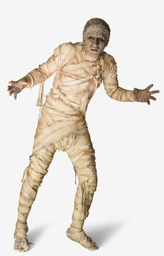 Man dressed up as a mummy for Halloween making stiff arm movements against a white background