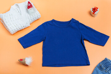 Blue kids raglan, polo shirt and knitted white jacket on colored background, top view close up, mock up with copy space