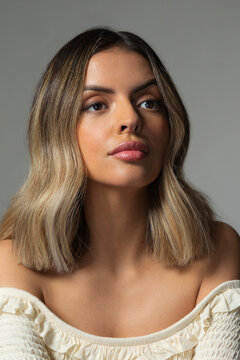 Confident young Hispanic woman looking up off camera against gray background