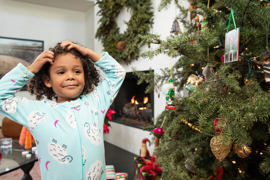 Young girl having fun while decorating Christmas tree in living room.