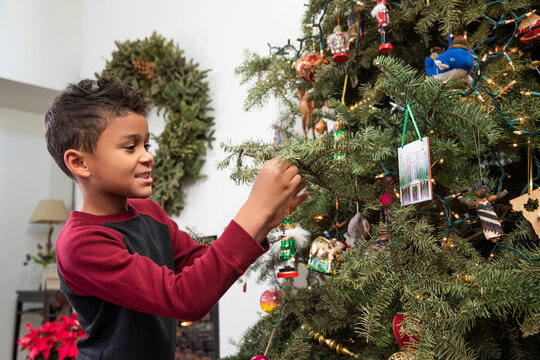 Little boy hanging Christmas decorations at home.