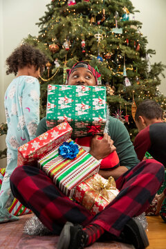 Man playing with his family in front of Christmas tree.