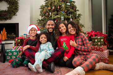 Christmas Card Portrait of a joyful young Black family sitting in front of Christmas tree