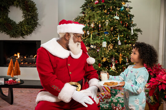 Cute seven year old girl bringing milk and cookies to Santa Claus