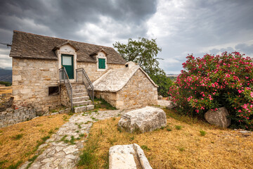 Old stone house with floral decoration on the forecourt, near Split town, Croatia, Europe. - obrazy, fototapety, plakaty