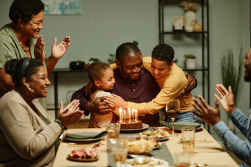 Portrait of smiling African-American man embracing children while celebrating Birthday with big happy family - Powered by Adobe