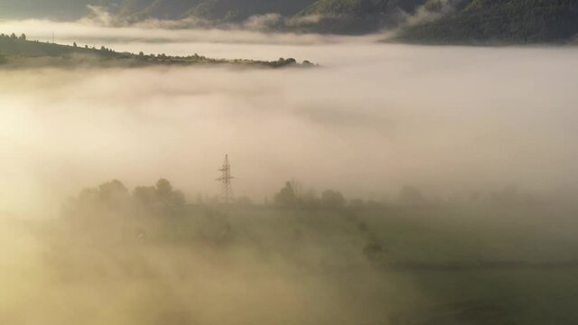 Aerial view on amazing flowing morning fog spreads over green meadows in autumn mountains. Ukrainian Carpathian mountains. UHD 4k video