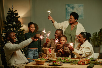 Portrait of big African-American family lighting sparklers while enjoying Christmas at home together