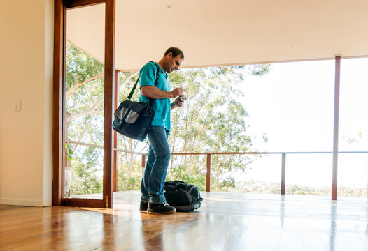 Man with packed bags closing up doors in house preparing to leave