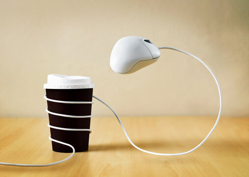 Take away coffee cup on desk and computer mouse wrapped around it