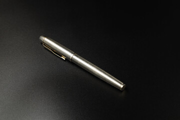 Metal pen on black background