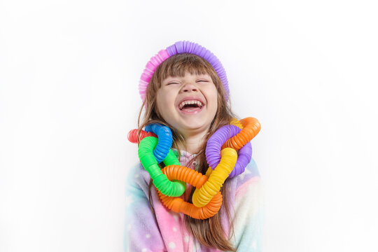 Cheerful little girl in unicorn pajamas plays in a popular toy poptube. An exciting children's game with multi-colored plastic pipes.