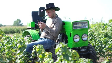A farmer in the middle of a vineyard writes a message on a smartphone,