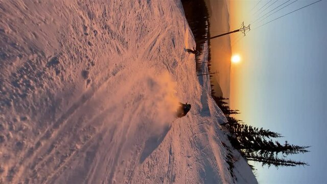 A skier falls hard on a ski slope against the background of sunset on a frosty day at a ski resort, vertical video
