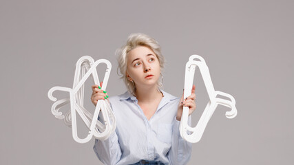 Girl holding a bunch of clothes hangers in her hands on a white background
