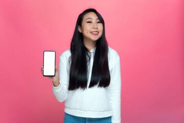 Smiling asian young girl showing phone with blank mock up screen presenting new mobile apps, advertising services