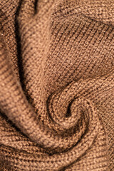 Knitted warm brown sweater. Cozy, composition in the home atmosphere. Wool fabric texture close up background. Comfortable style clothing. pulover is turned in waves. Soft focus