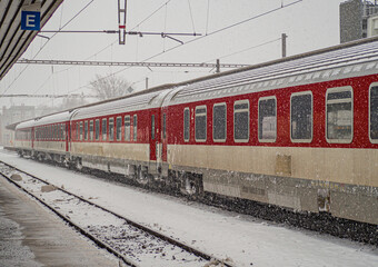 Fototapeta premium A snow-covered railway platform with a passenger train.