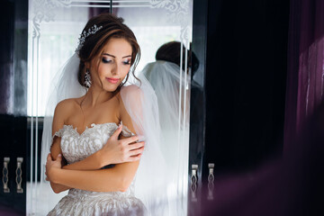 Getting ready for the wedding. Beautiful young bride in a white wedding dress in the room. Morning of the bride.
