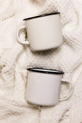 White metal cups mockup. White knitted sweater background. Perfect for presentations, decor and design.