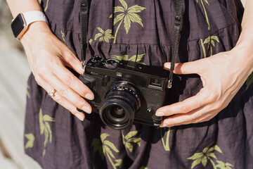 Tourist traveler photographer making pictures holding photo camera on dress with palms background, relax holiday