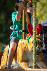 An Animal Themed Carrousel with a Young Girl Riding a Mountain Lion Figure and Holding on Tight