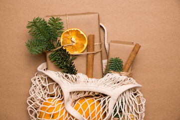 Gifts wrapped in craft paper and decorated with dry oranges and cinnamon sticks in string reusable...