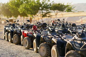 Fototapeta na wymiar Many atv quad motorbikes standing in the mountains with trees in background, on a sunny day