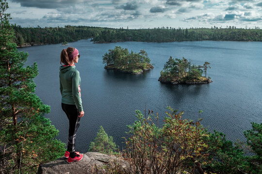 Woman standing in front of small islands in Lake Stensj&ouml;n in the Tyresta National Park in Sweden, during day with clouds in sky, from above.