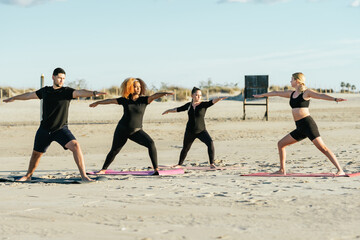 Yoga teacher conducting a class with multiethnic people on a beach