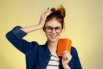 woman student with glasses notepad with pen yellow background