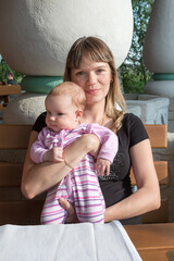 mom and baby sit at a table in a restaurant